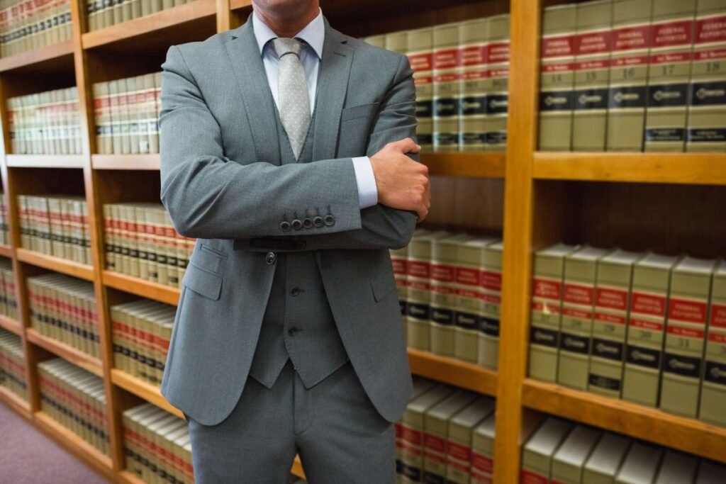 Avocat droit routier bras croisés devant une bibliothèque de codes juridiques