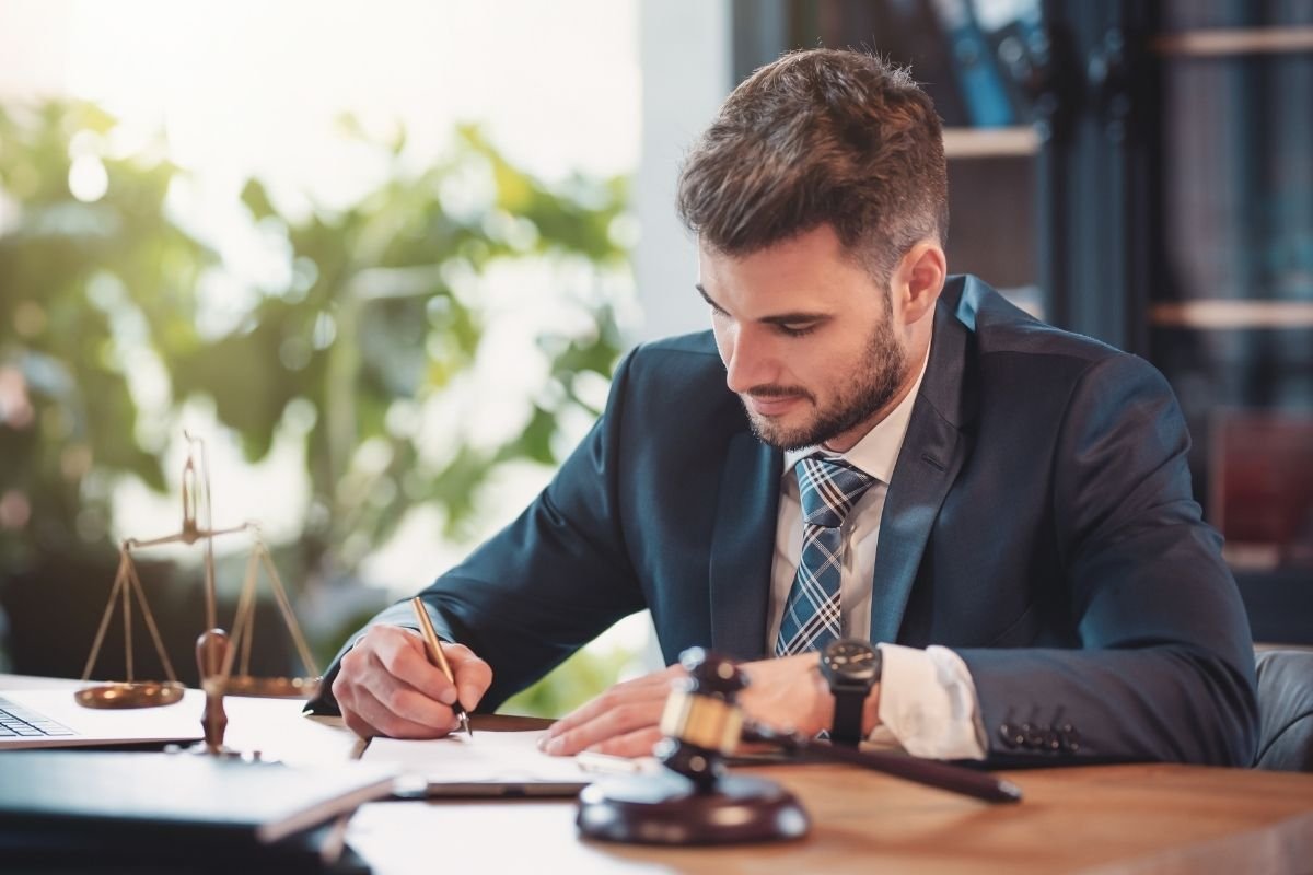 Avocat en droit routier signe un dossier lors d'une consultation, balance de la justice posée sur le bureau