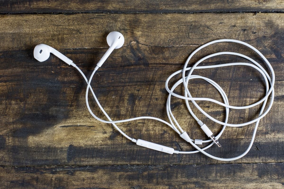Écouteurs filaires blancs avec câble posés sur une surface en bois, dispositif audio interdit au volant