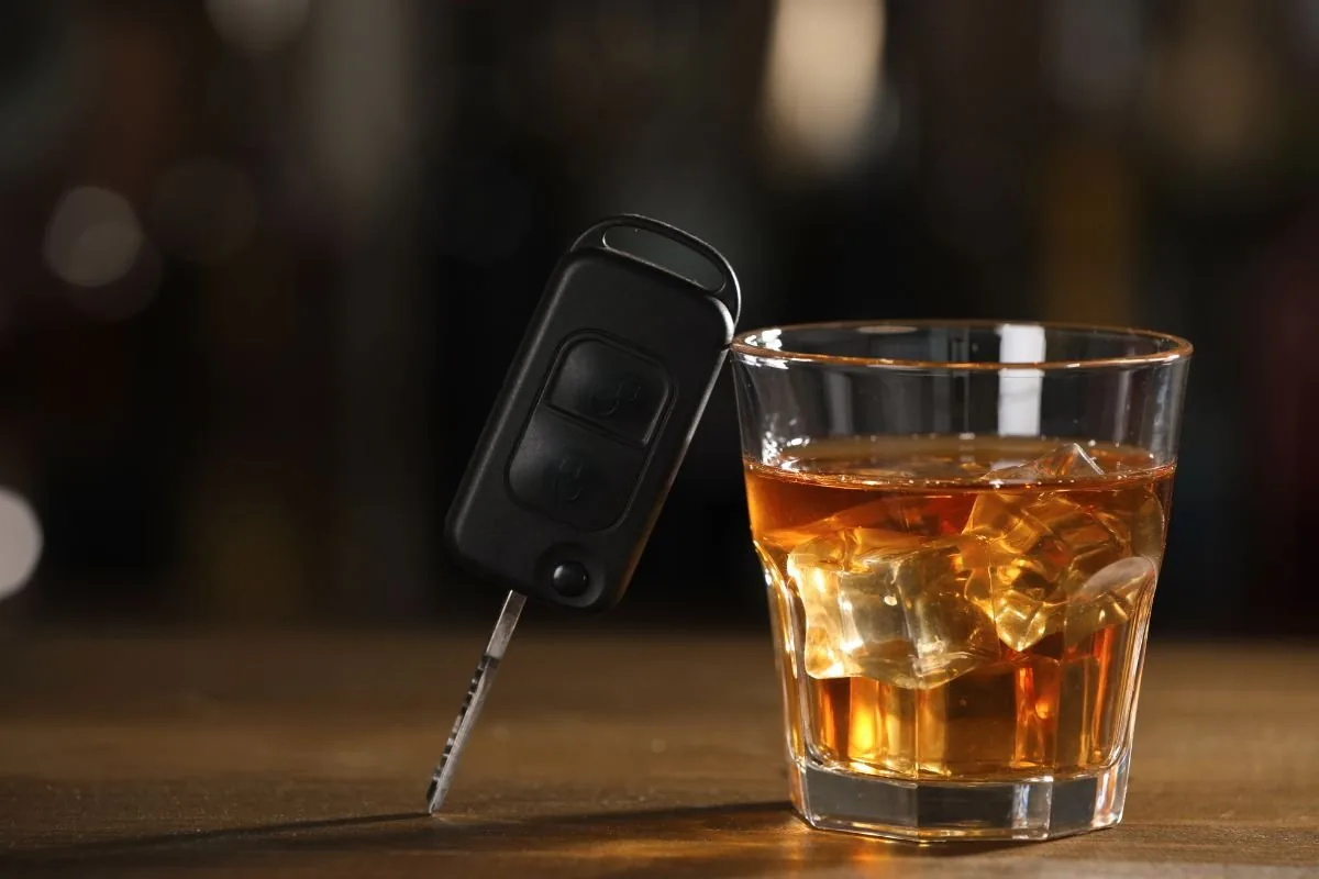 Clé de voiture posée contre un verre d'alcool, illustration de l'alcool au volant