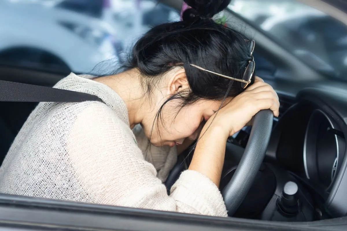 Conductrice la tête posée sur le volant, illustration des conséquences de l'alcool au volant