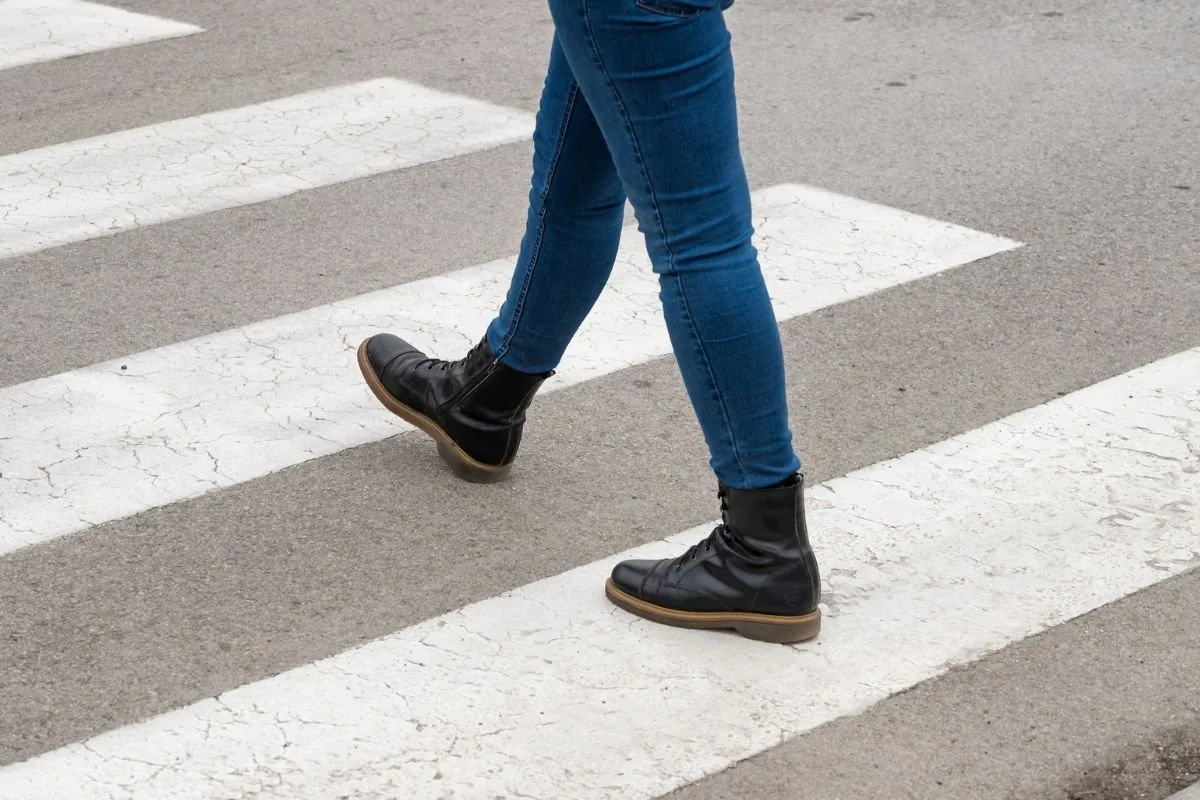 Piéton traversant sur un passage clouté, jambes en mouvement
