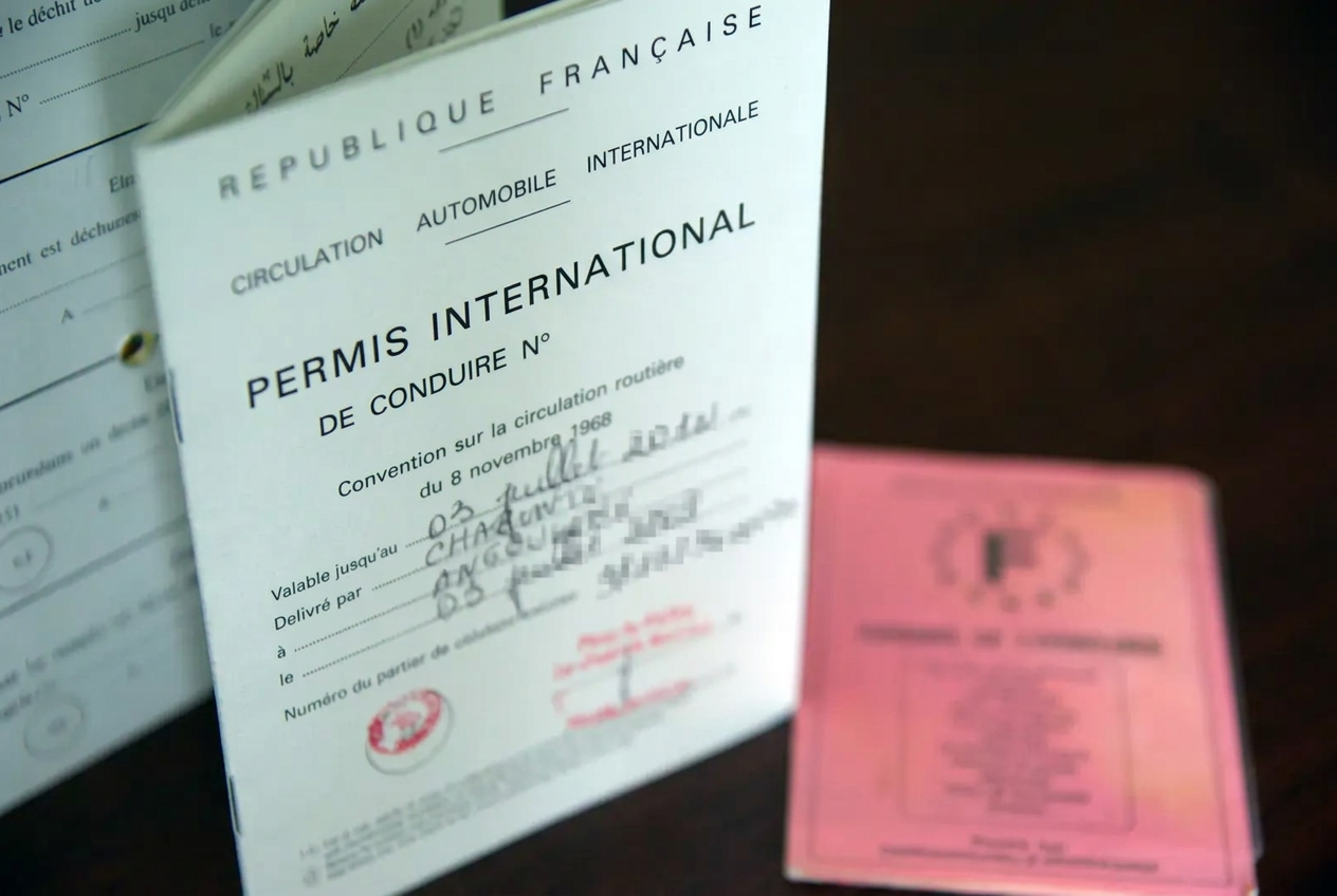 Permis international de conduire français ouvert à côté d'un permis national, document pour conduire à l'étranger
