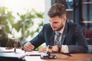 Avocat en droit routier signe un dossier lors d'une consultation, balance de la justice posée sur le bureau